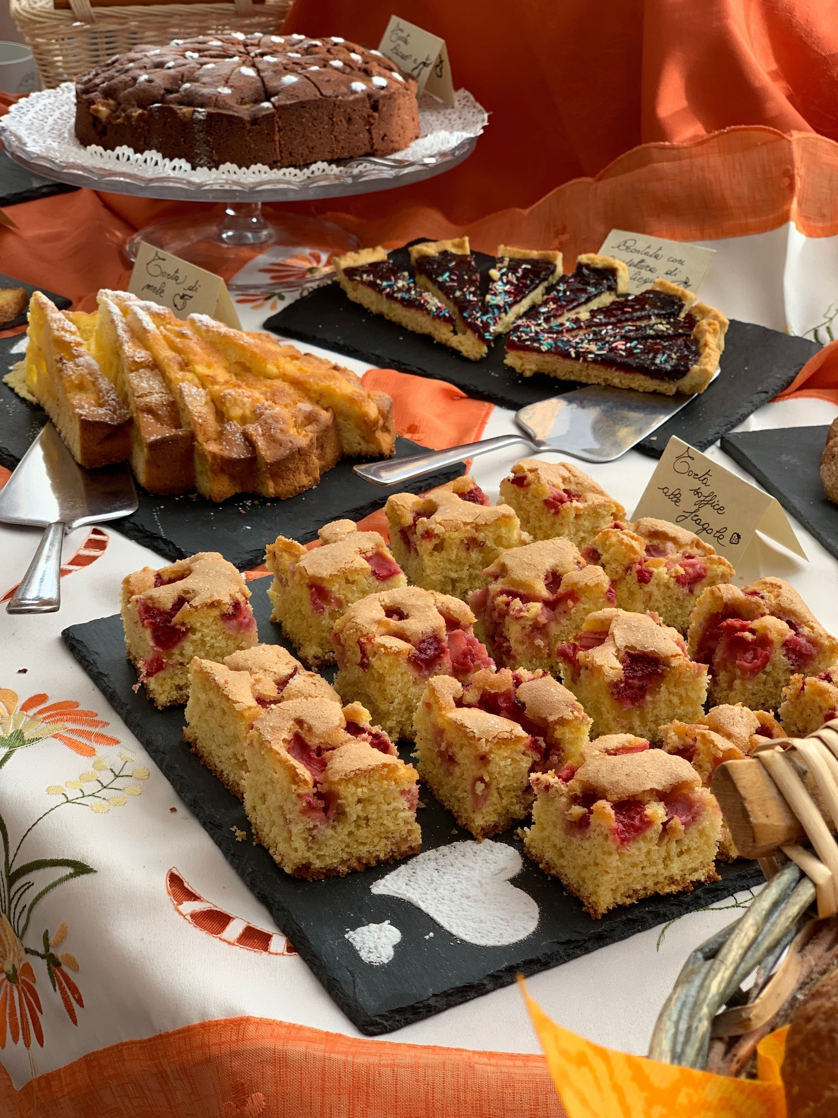 A variety of desserts on a table, including a chocolate cake, a tart, and several fruit tarts.
