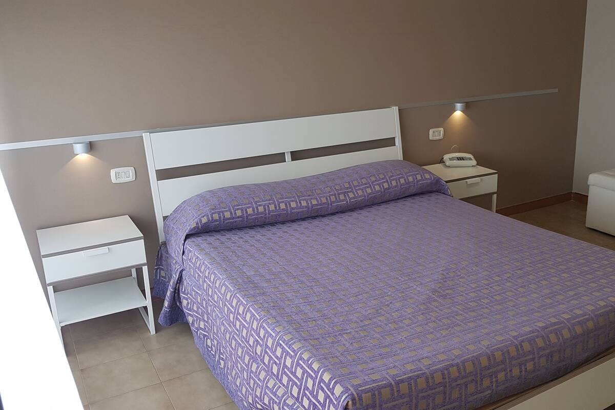 A bedroom with a bed, nightstands, a bedside table, and a storage bench.