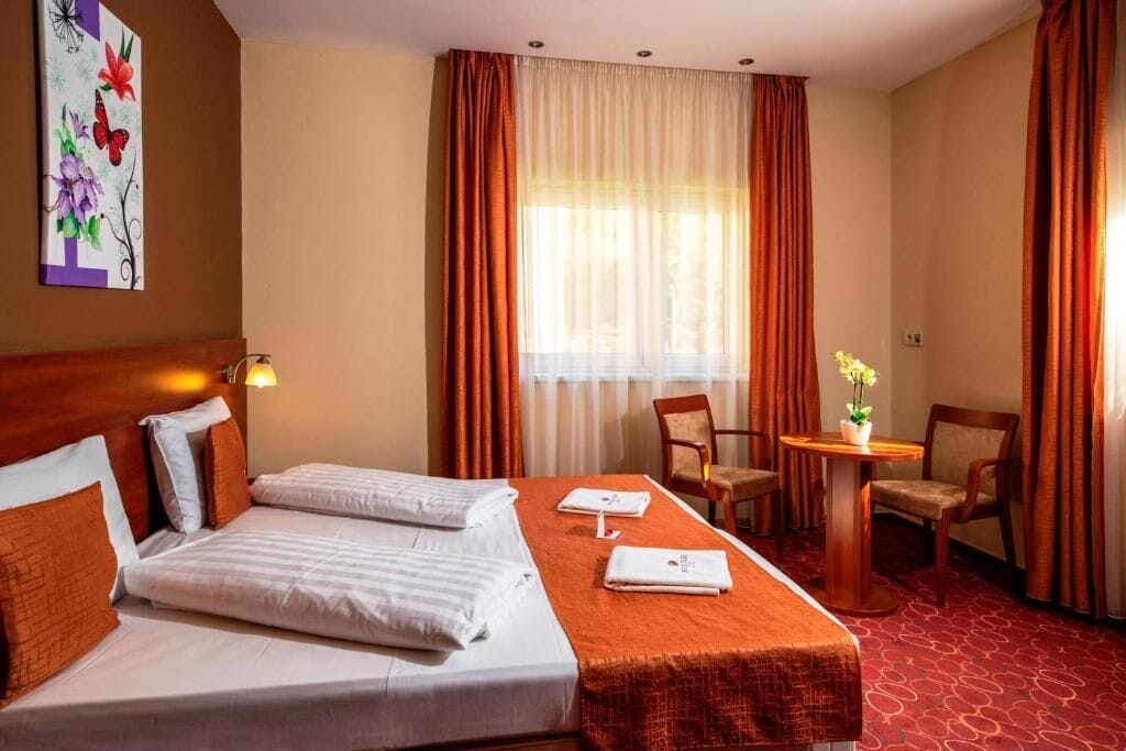 A hotel room with two beds, a desk, and a chair.