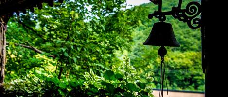A bell hanging from a structure with a view of lush greenery in the background.