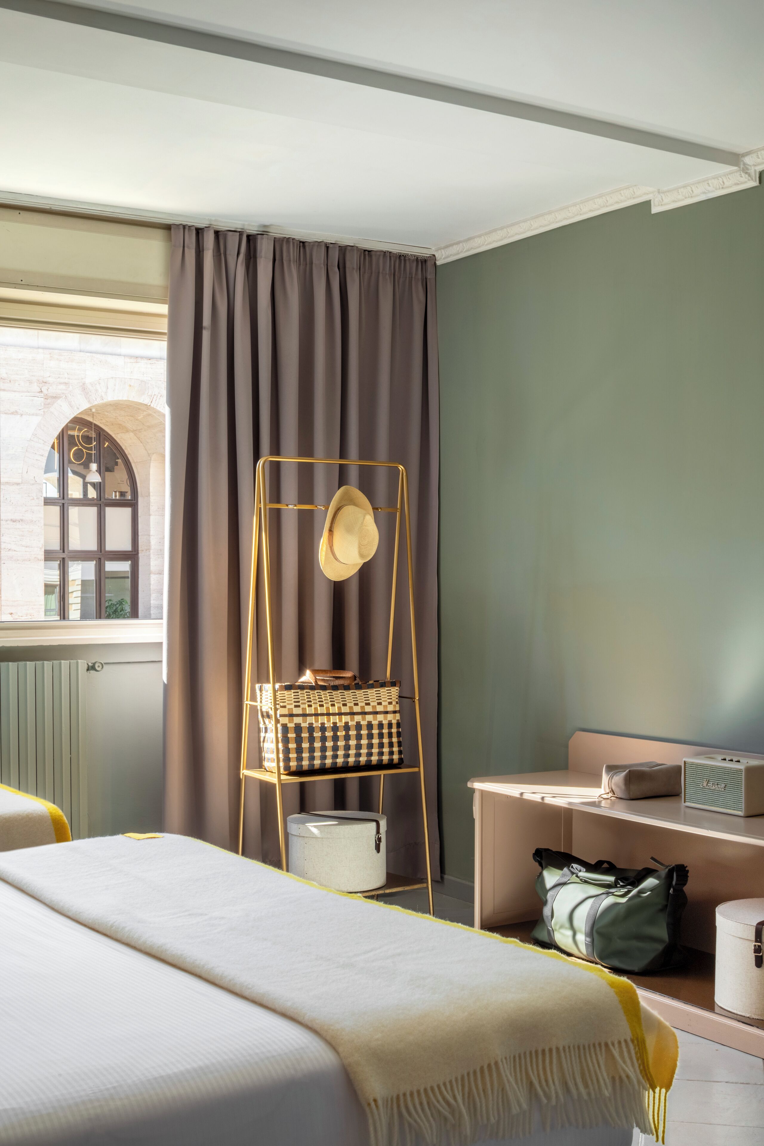 A hotel room with a bed, a desk, a chair, and a window with curtains.
