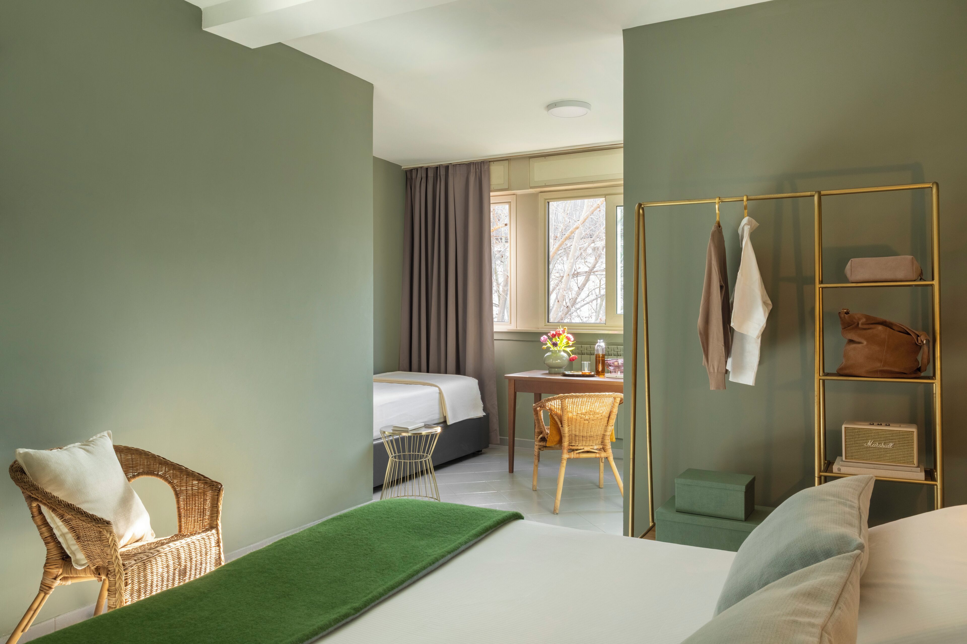 Una habitación de hotel con cama, una silla, un escritorio y una ventana con cortinas.