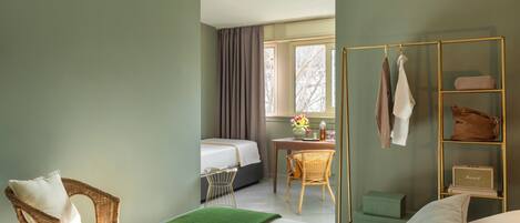 Una habitación de hotel con cama, una silla, un escritorio y una ventana con cortinas.