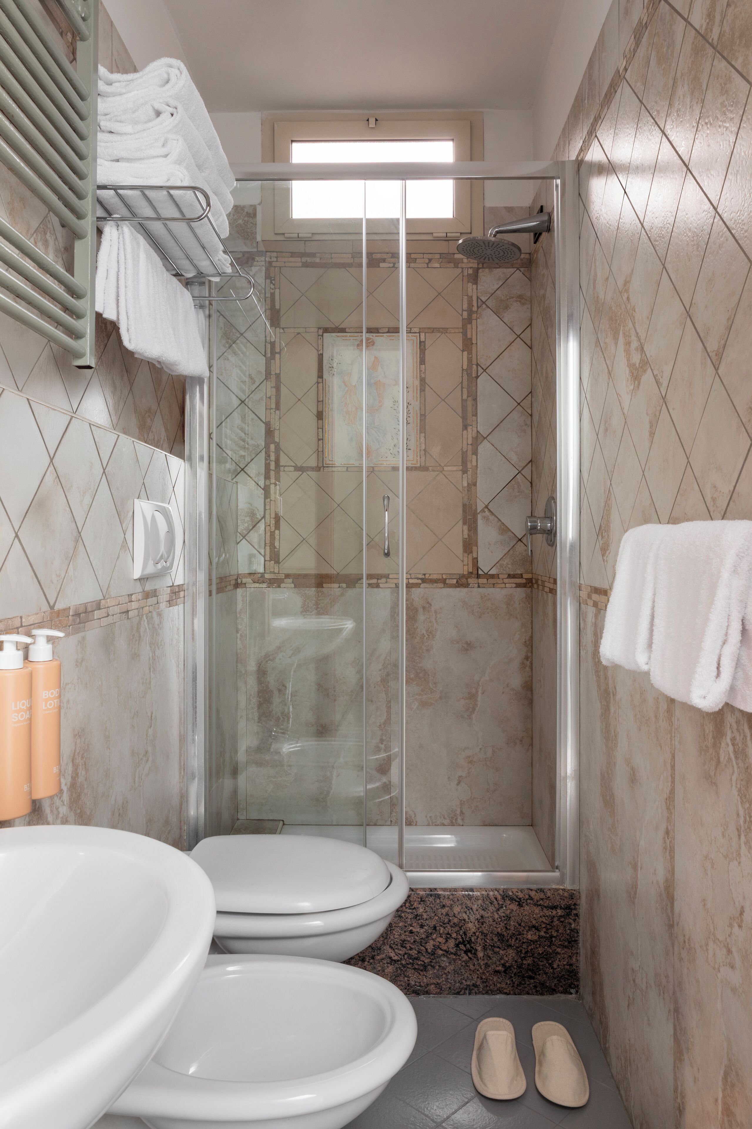 Ein Badezimmer mit Duschkabine, zwei Toiletten, einem Waschbecken und einem Handtuchhalter.