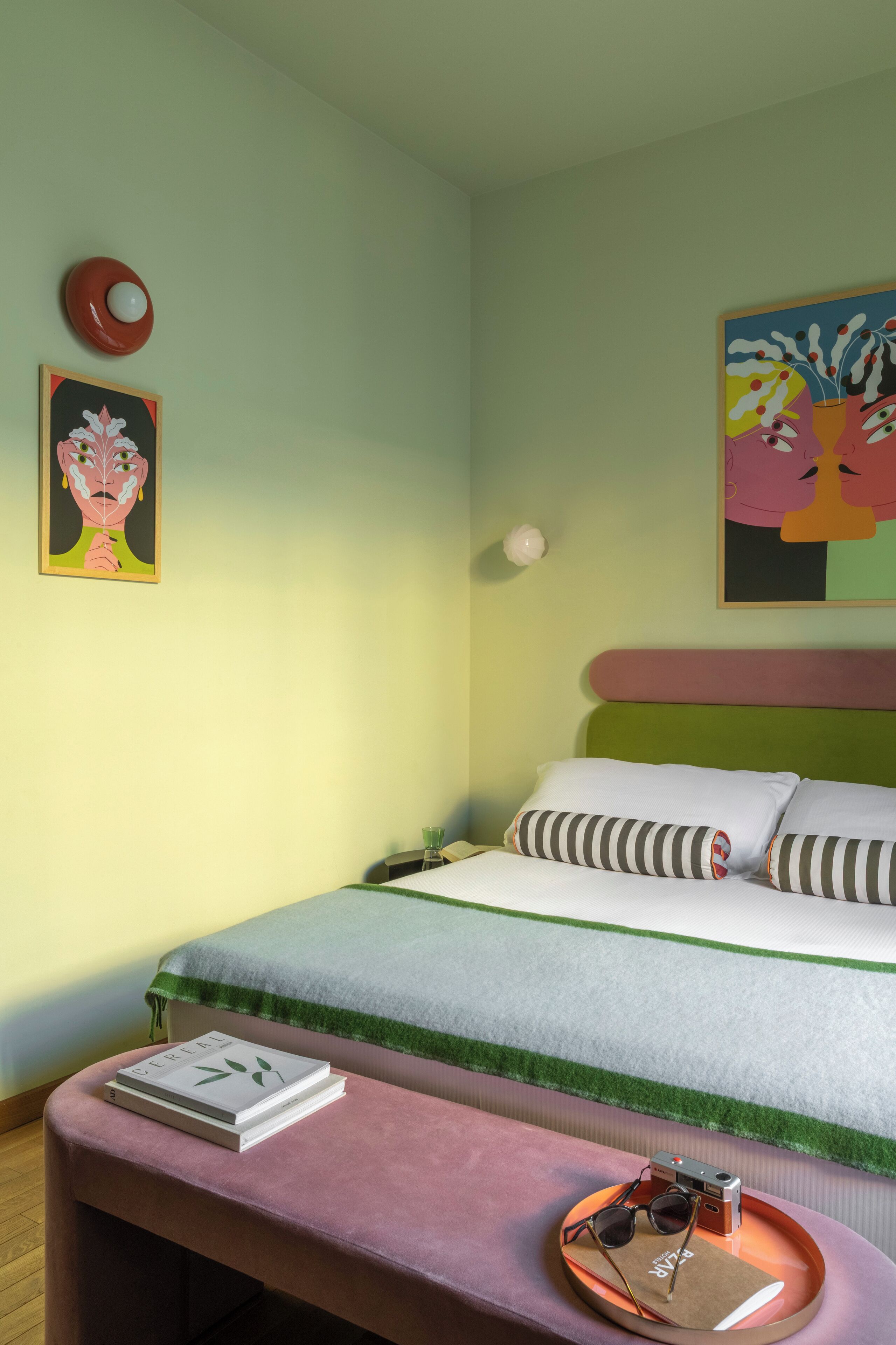 Une chambre à coucher avec un lit, une table de chevet, une horloge murale et un tableau encadré.