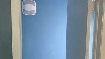 Una habitación con pared azul, techo blanco y puerta con picaporte de latón.