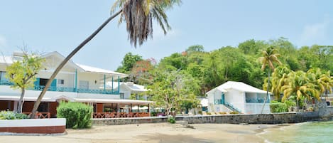 A beachfront hotel with multiple buildings, palm trees, and a sandy beach.