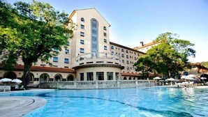 Un hotel con piscina, un patio central y un edificio grande con muchas ventanas.