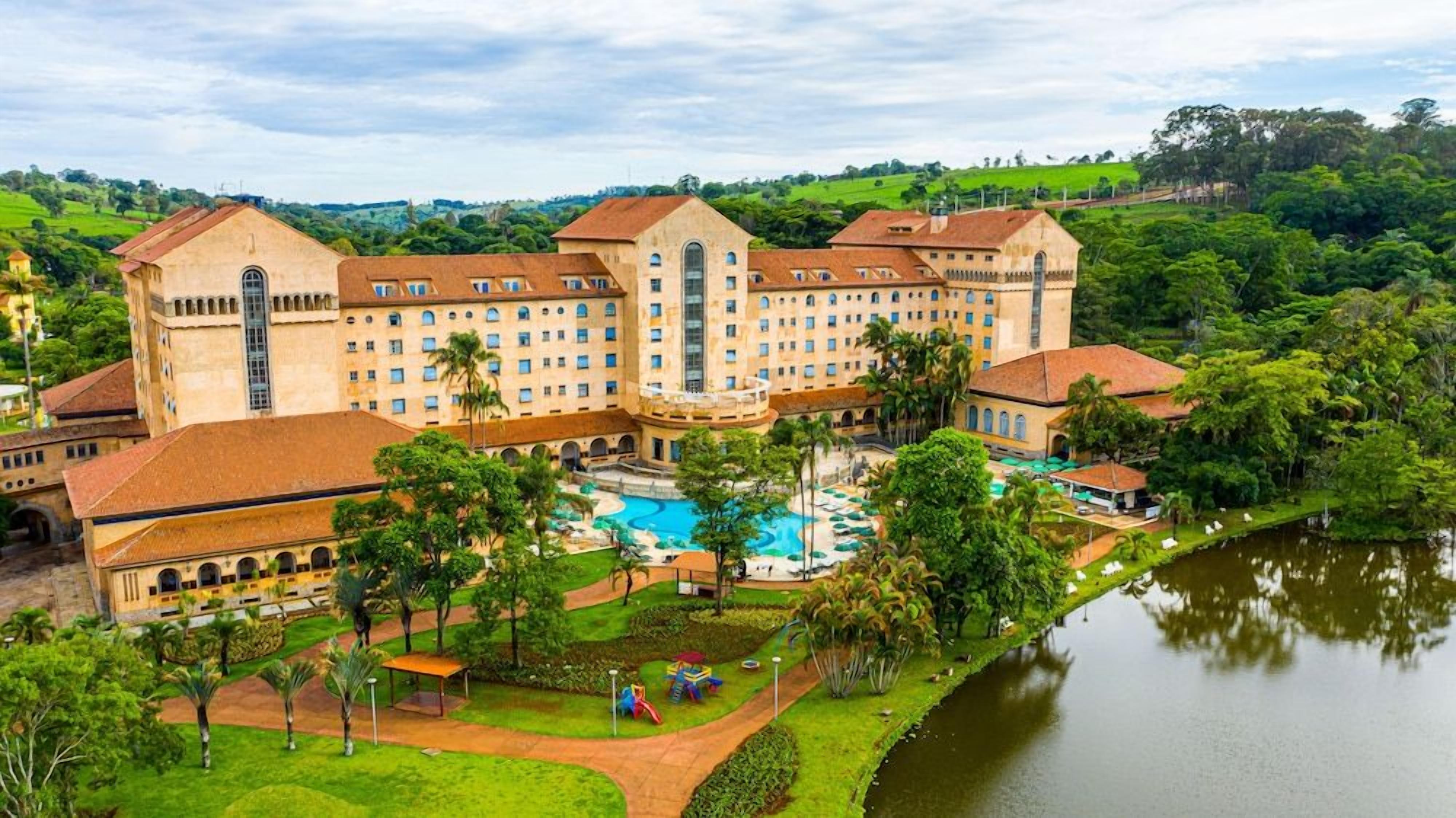A large hotel with multiple buildings, a swimming pool, and a lake.