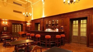 Zona de bar con mobiliario de madera, un piano y una barra.