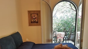 Un dormitorio con cama, cómoda, un cuadro y vistas por la ventana.