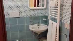 Un baño con inodoro, lavamanos y toallero.