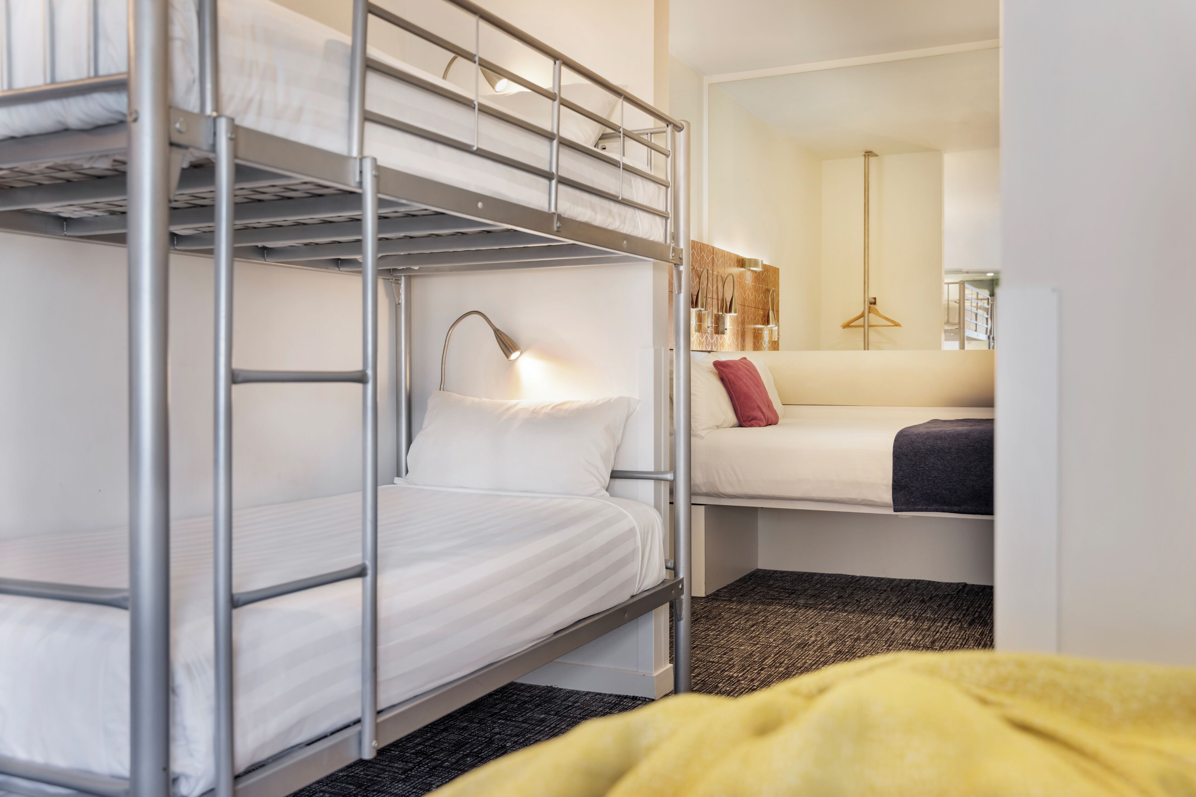 Une chambre avec un lit superposé, un bureau et une chaise, une lampe et un miroir.