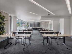 Uma sala de conferências moderna com mesas, cadeiras e um projetor.