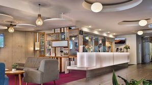 A modern hotel lobby with a reception desk, seating area, and a TV screen. - BreakFree on Cashel Christchurch (Christchurch)