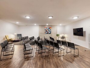 Uma sala de conferências com uma mesa comprida, várias cadeiras, um sofá, uma planta e obras de arte nas paredes.