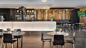 A modern bar area with a counter, bar stools, and a television screen. - BreakFree on Cashel Christchurch (Christchurch)