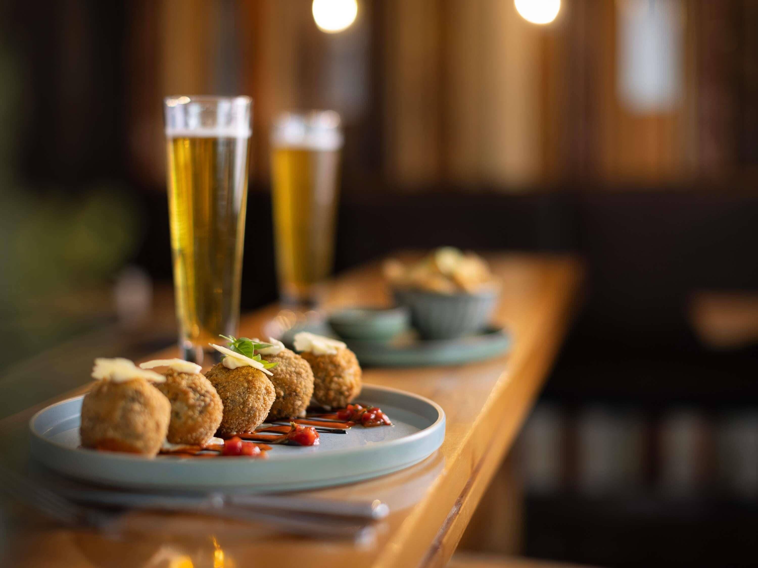 A bar setting with plates of food and glasses of beer.