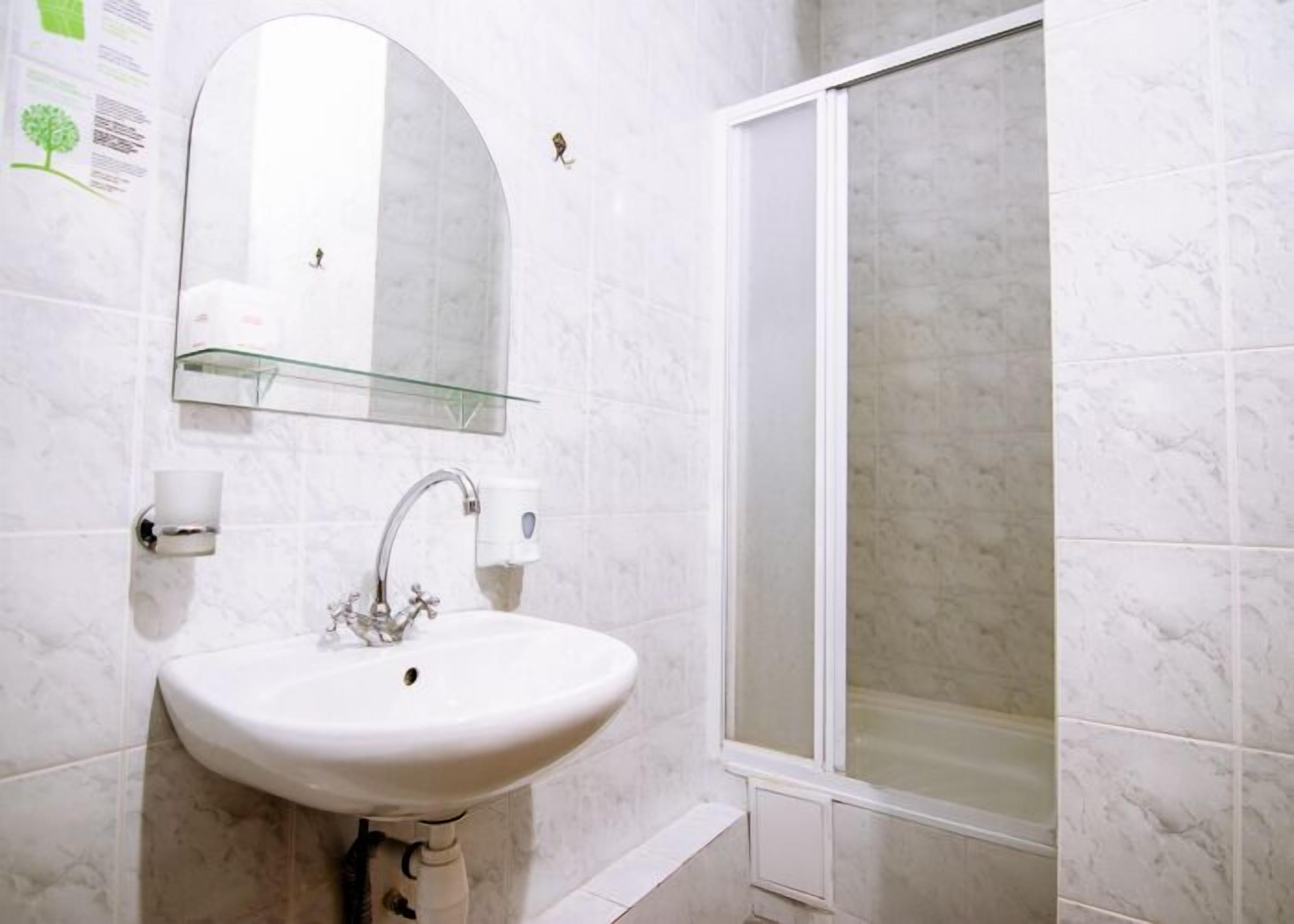 A bathroom with a white sink, a mirror, and a shower.