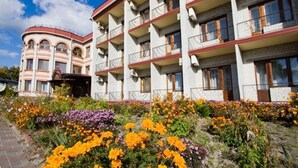 A multi-story hotel with balconies and a garden with colorful flowers.