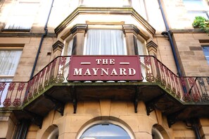 A building with a sign reading "THE MAYNARD" above a balcony with ornate metal railings. - The Maynard (Scarborough)