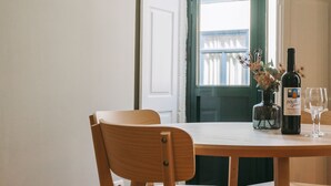 A dining area with wooden chairs and a table, a bottle of wine, and a glass. - Oporto Maison Sol   (Porto)
