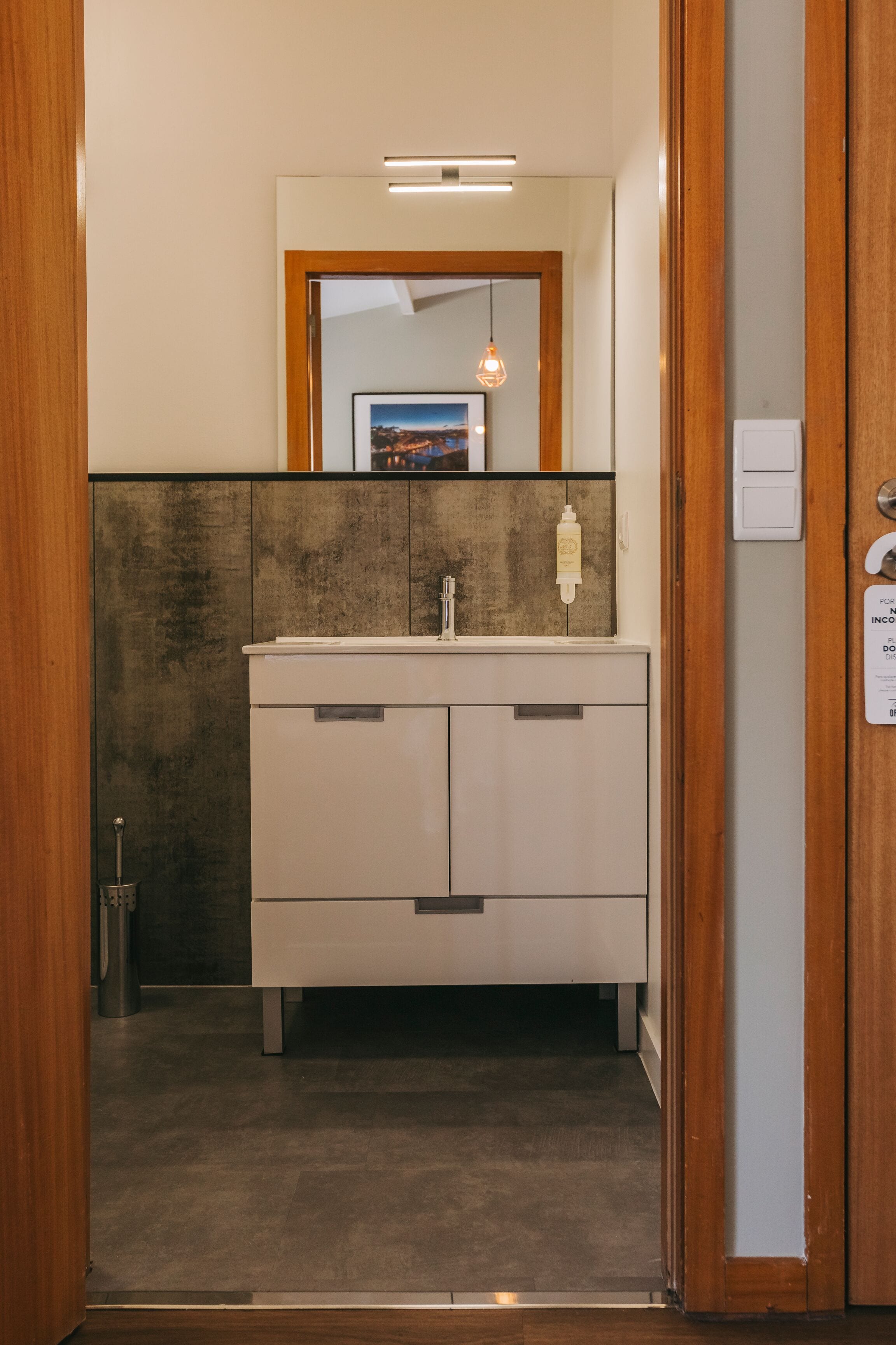 Une salle de bain moderne avec une porte en bois, un lavabo blanc et un miroir au-dessus.