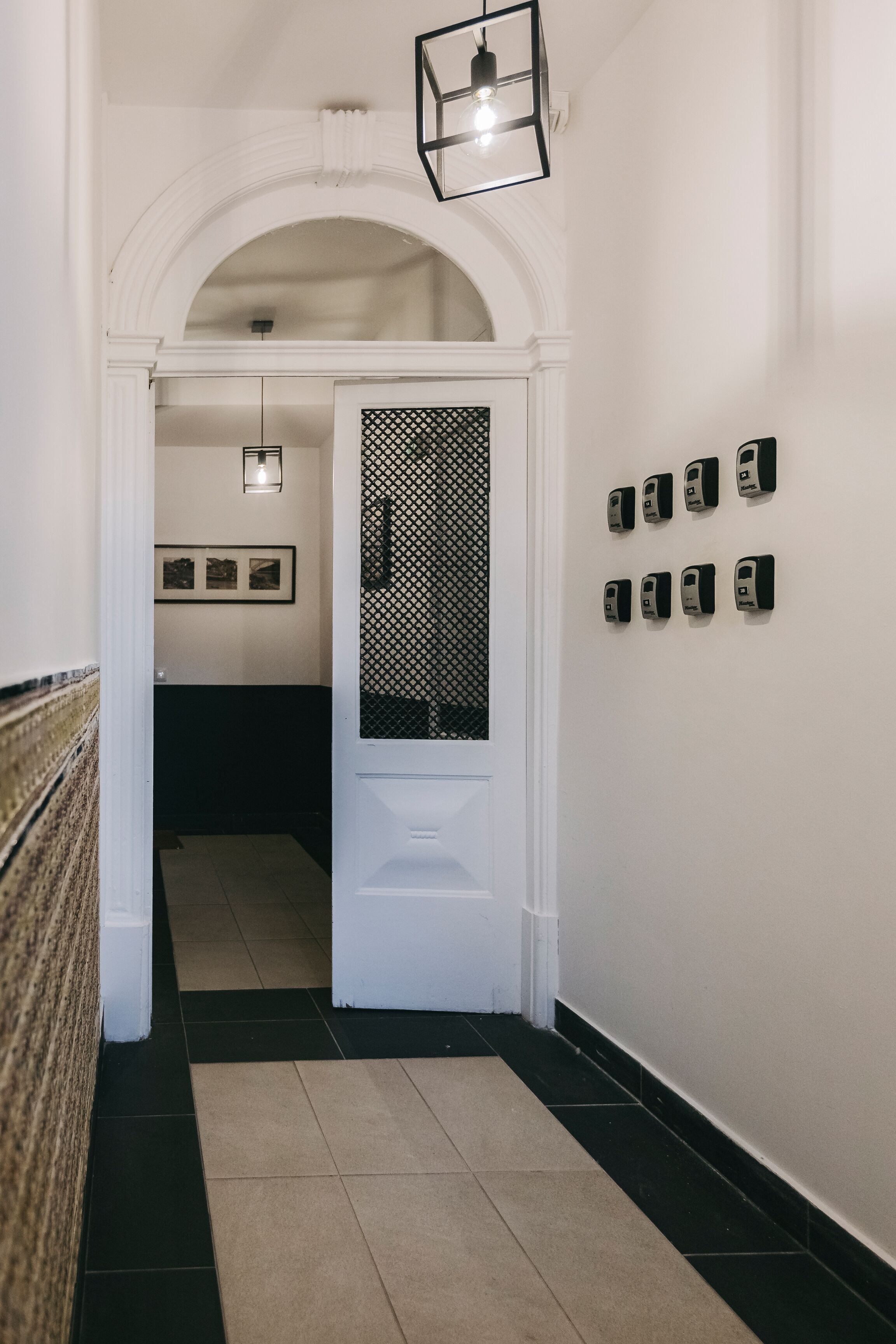 A hallway with a white door, a patterned wall, and a series of black objects on the wall.