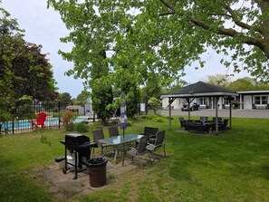 Un espace patio aménagé avec du mobilier d’extérieur, un barbecue et un coin salon abrité.