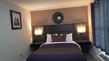 A hotel room with a large bed, two bedside lamps, a wall-mounted mirror, and a framed picture.