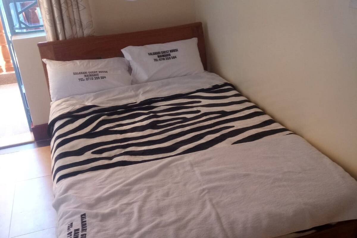 A bed with a zebra-striped bedspread, two pillows with text, and a wooden headboard.