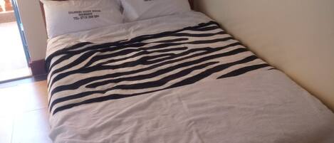 Una cama con una colcha a rayas de cebra, dos almohadas con texto y un cabecero de madera.