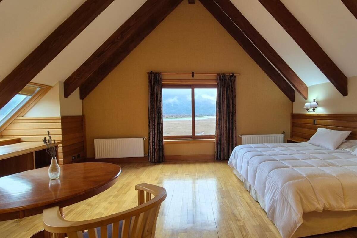 Ein Schlafzimmer mit einem großen Bett, einem Holztisch und einem Fenster mit Vorhängen.
