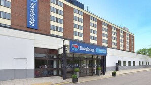 Un hotel Travelodge con una fachada moderna, amplios ventanales y un cielo despejado.