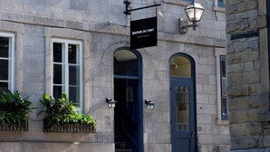 A stone building with multiple windows, a blue door, and a sign reading "MAISON DU FORT". - Hôtel Maison du Fort (Québec City)