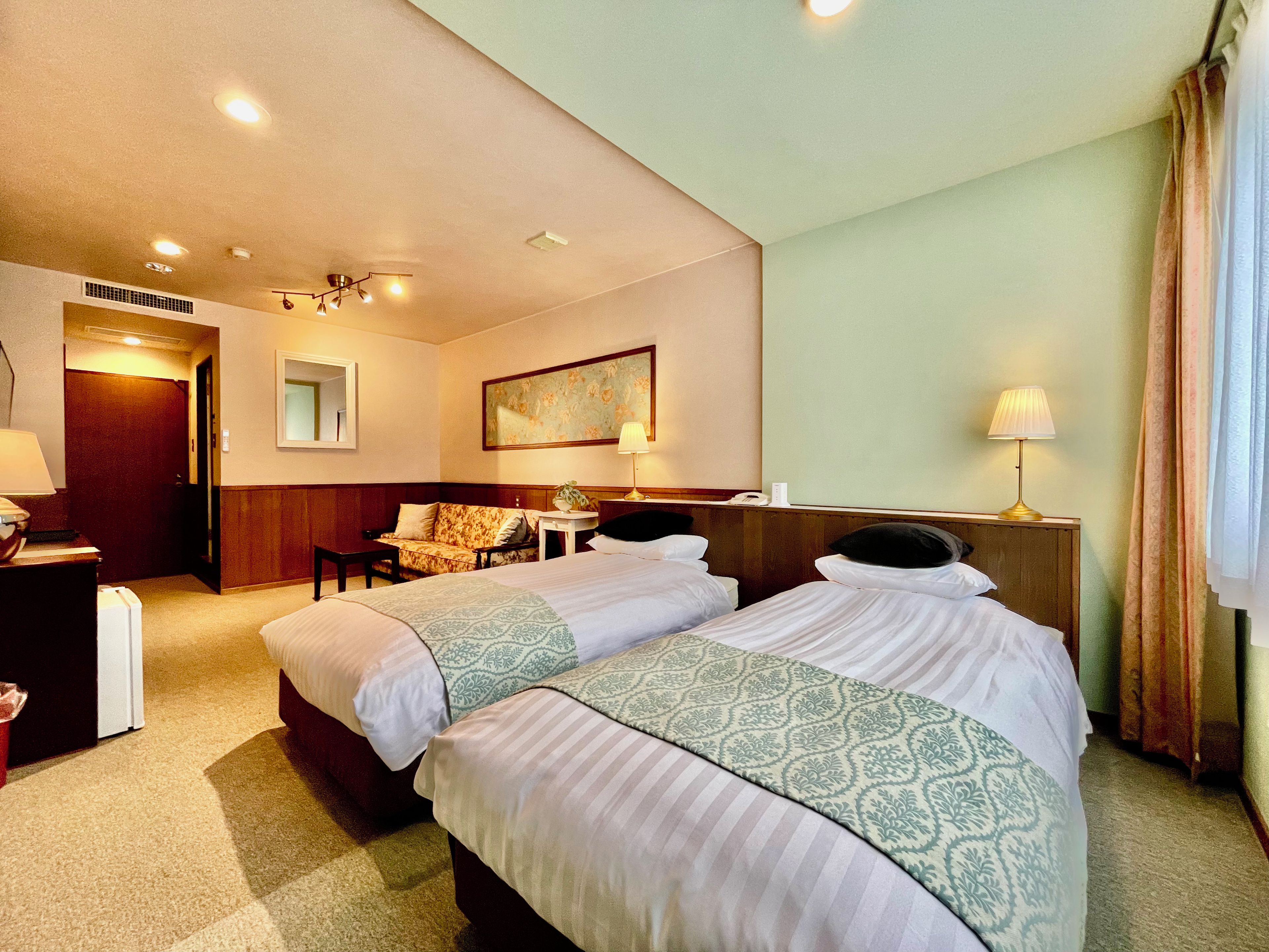 Una habitación de hotel con dos camas, un sofá, un escritorio y un espejo.