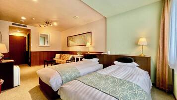 Una habitación de hotel con dos camas, un sofá, un escritorio y un espejo.