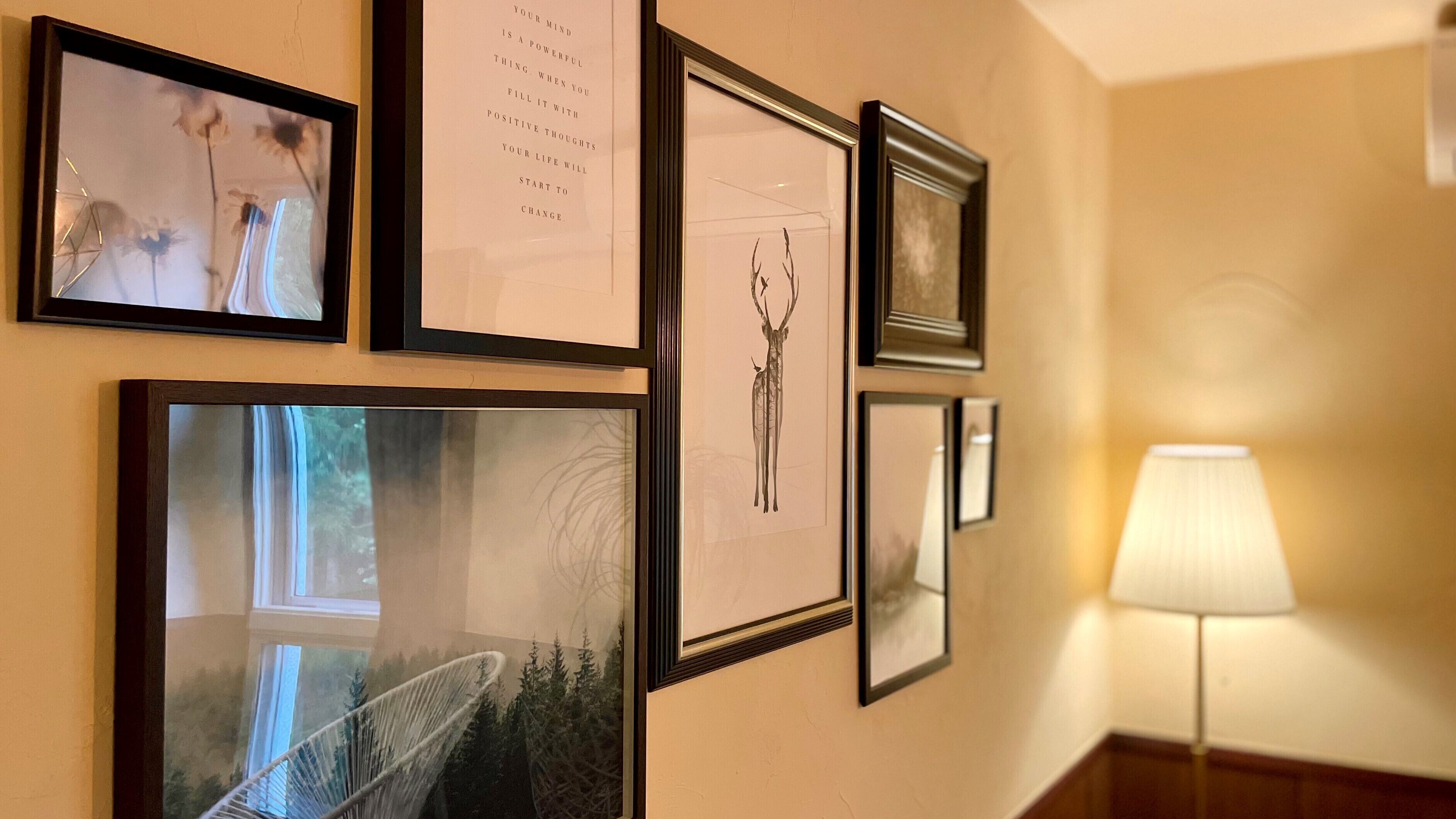 A hallway with framed artwork on the wall, including a deer illustration and a text poster.