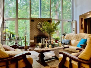 Una sala de estar acogedora con chimenea, sofás de cuero y un ventanal con vistas a un bosque.