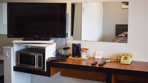 A hotel room with a flat-screen TV, a microwave, a coffee maker, a telephone, and a mirror on the wall. - Elect Inn 5 (Cornwall)