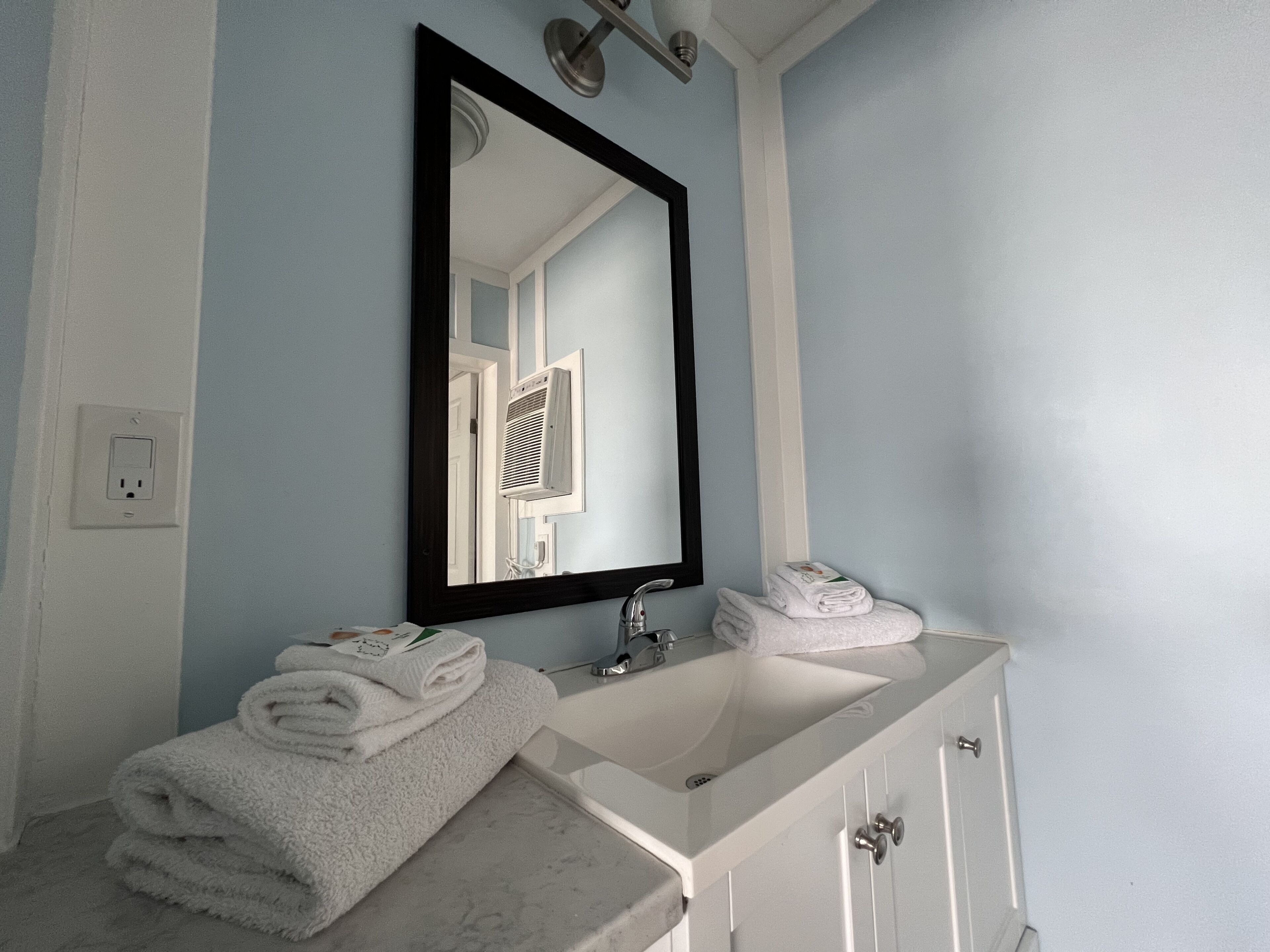 A bathroom with a white sink, a mirror, and a towel rack.