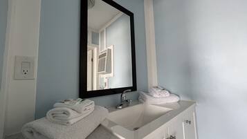 A bathroom with a white sink, a mirror, and a towel rack.