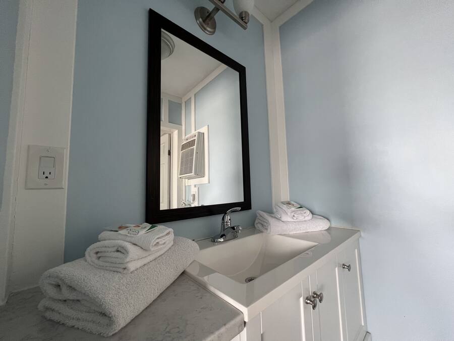 A bathroom with a white sink, a mirror, and a towel rack.