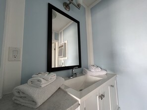 A bathroom with a white sink, a mirror, and a towel rack.