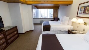 A hotel room with two beds, a desk, a chair, a television, and a window with a city view. - J&A Classic Hotel (Lima)