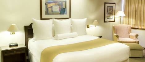 A hotel room with a large bed, a chair, a nightstand, and two wall-mounted lamps.