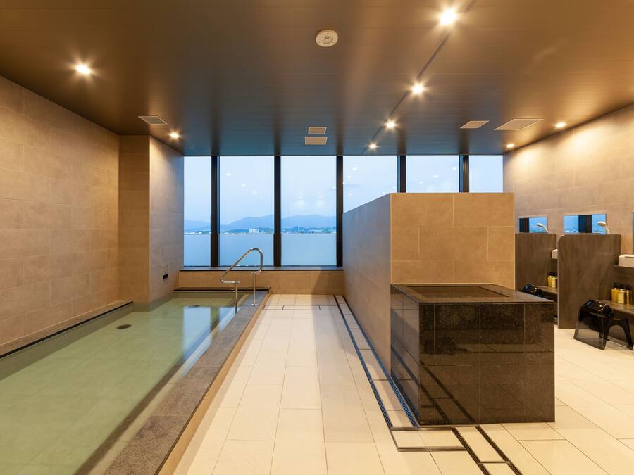 Piscina interior moderna com vista para as montanhas, área de sauna e um balcão de recepção.