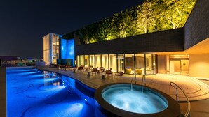 Een modern hotel met een zwembad op het dak, terras en een jacuzzi.