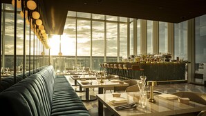 Een restaurant met een lange toonbank, hoge stoelen en een bar.