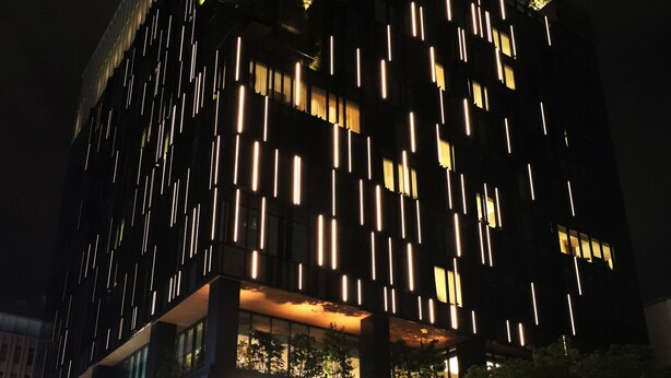 Een modern gebouw met een opvallende gevel, voorzien van verticale lichtstroken en een glazen entree.